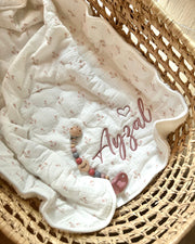 Baby blanket with 'Ayzal' embroidery in a wicker basket