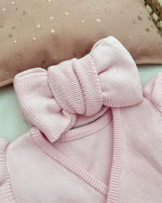 Pink knitted headband with a large bow on a soft pink background