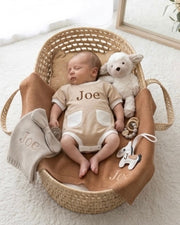 Baby in a basket with personalized clothing and toys