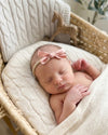 Newborn baby sleeping in a basket wearing a tiny light pink bow headband - Eli&Eli