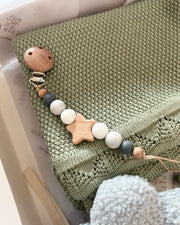Wooden teething toy with beads on a textured surface
