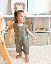 Summer romper play suit in olive muslin double gauze fabric with white rainbow print buttons at the from chest and down for easy diaper change 
