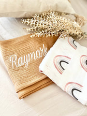 Baby swaddle blanket with personalised name in brown and rainbow print 