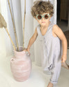 boy wearing a grey linen jumpsuit with boho green sunglasses